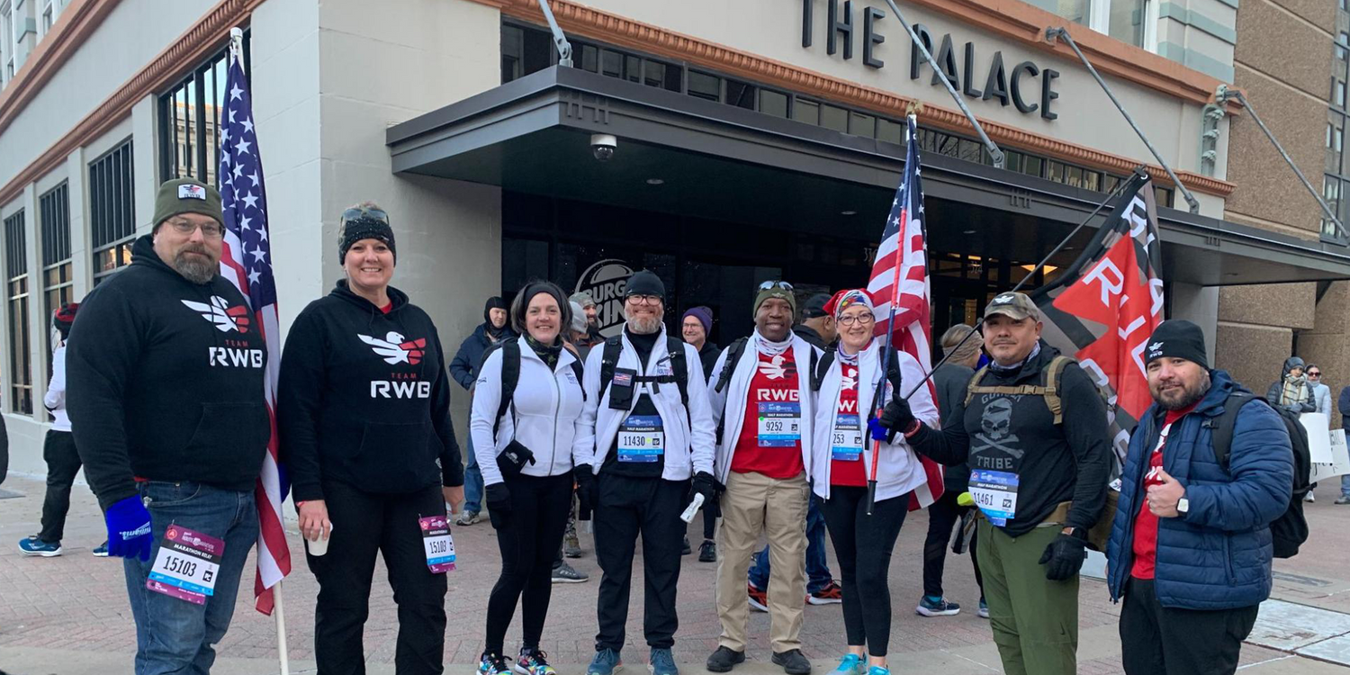 GORUCK participants in Team RWB gear with flags outside The Palace, ready for rucking event