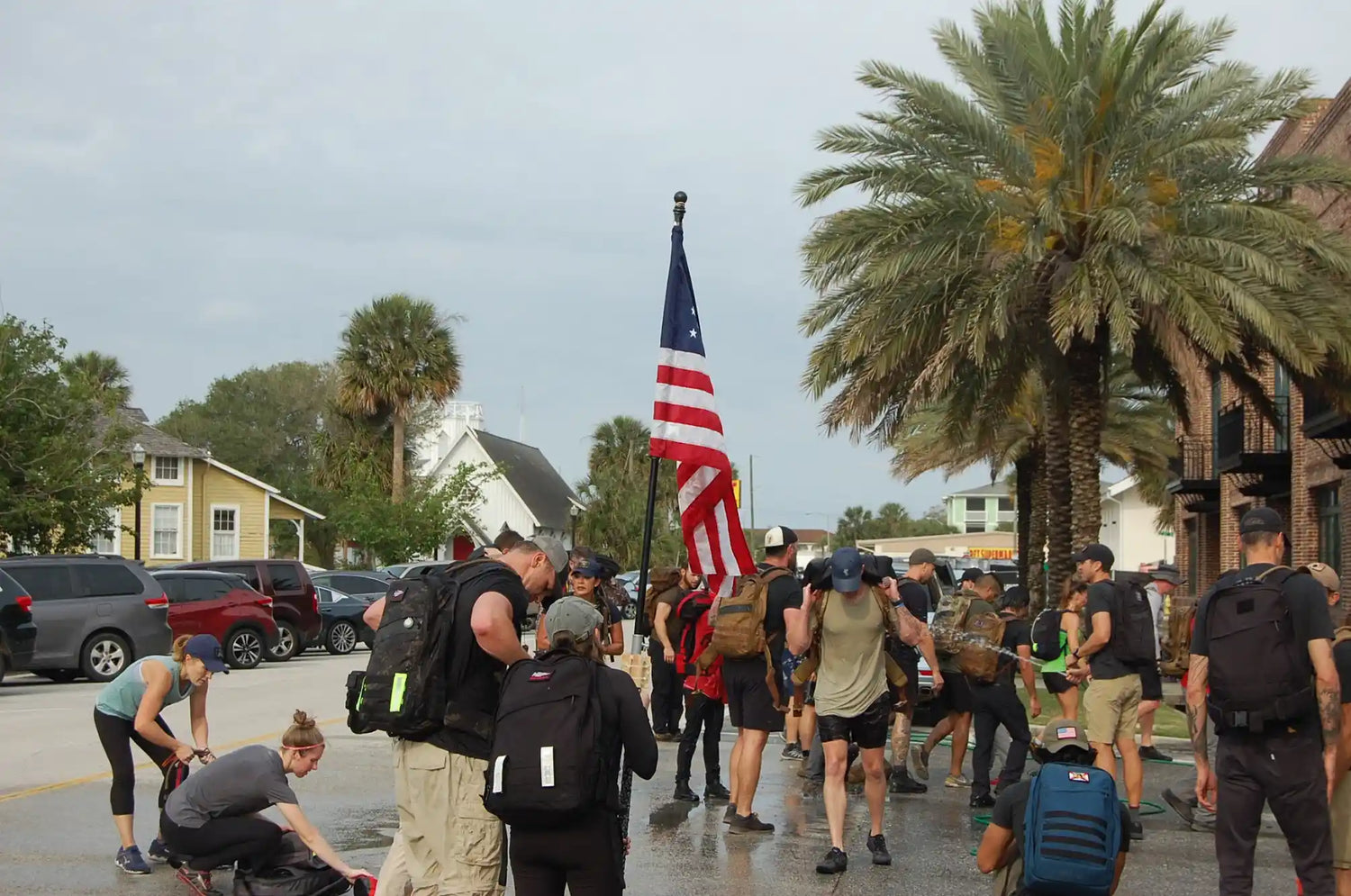 Group rucking event with GORUCK gear, American flag, and palm trees in urban setting