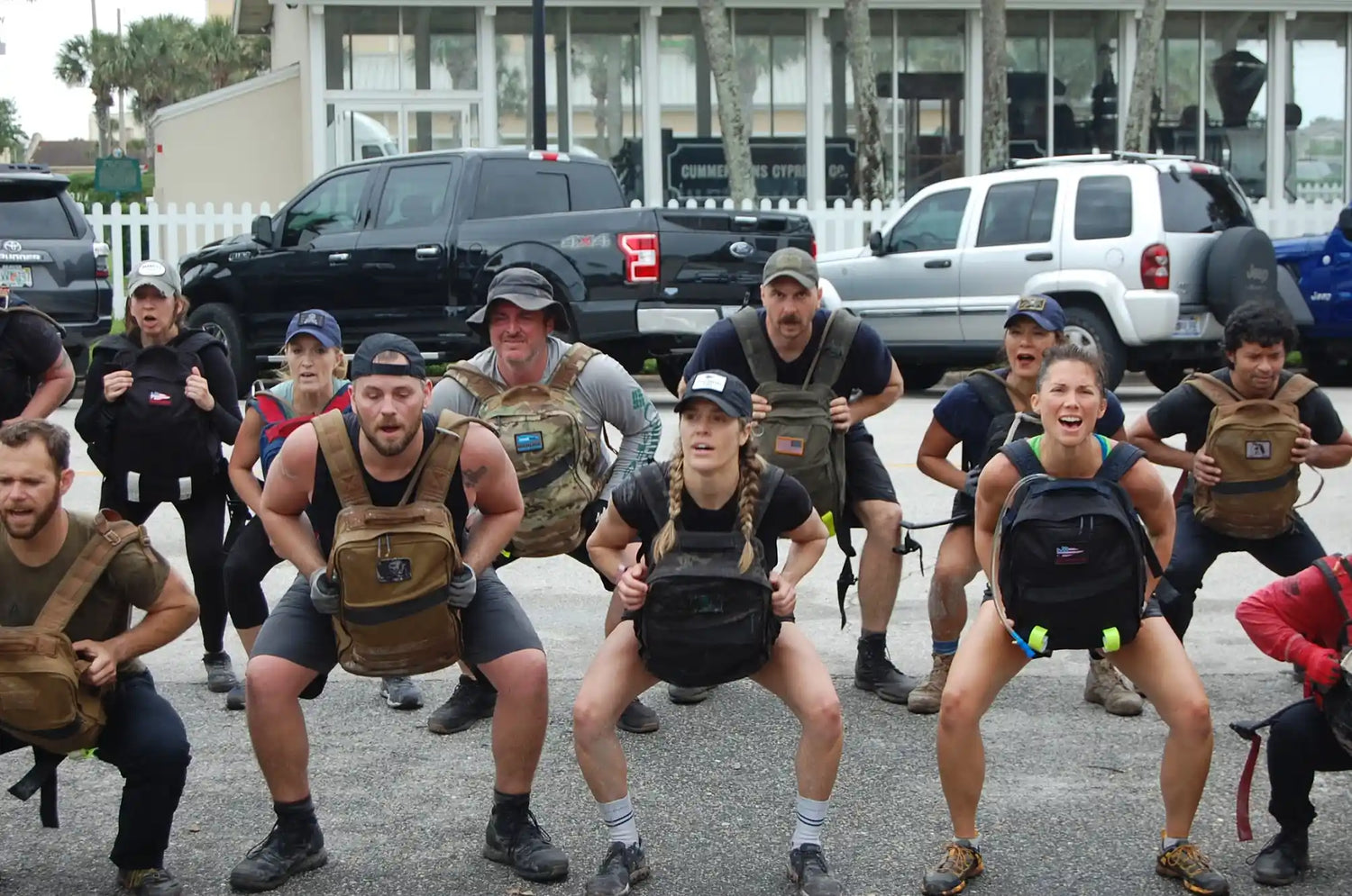 Group of people outdoors doing squats with GORUCK rucksacks during a rucking workout