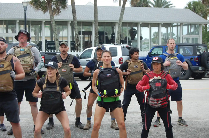 Group of people doing outdoor rucking exercise with GORUCK backpacks in a parking lot