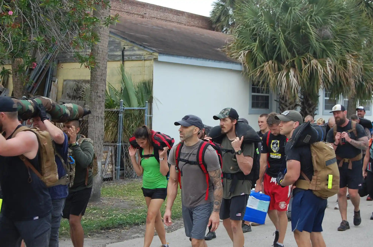 Group of people rucking outdoors with weighted backpacks and sandbags during GORUCK event