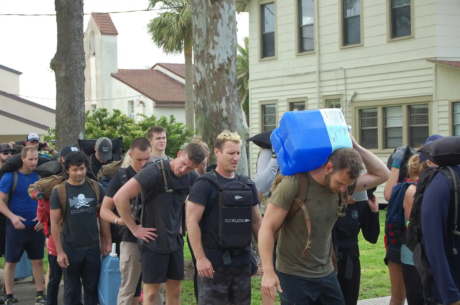 GORUCK participants rucking outdoors with backpacks and weighted gear during a team event