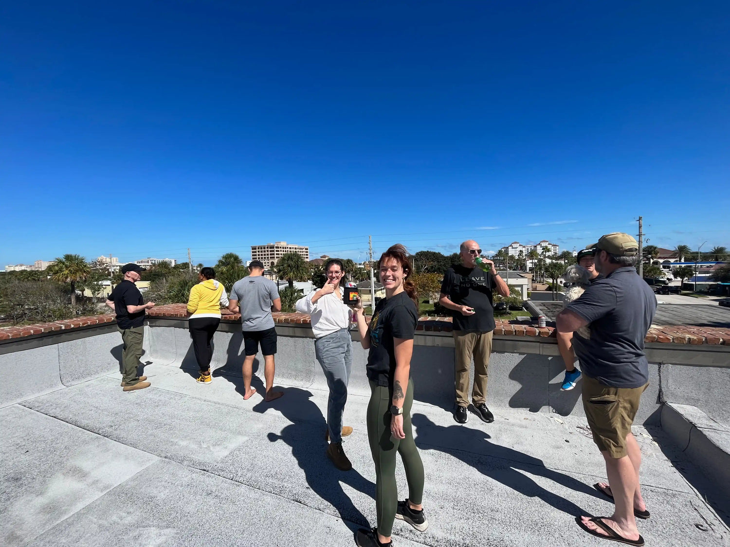 Group of people enjoying sunny rooftop gathering, goruck.mommunity, city skyline in background