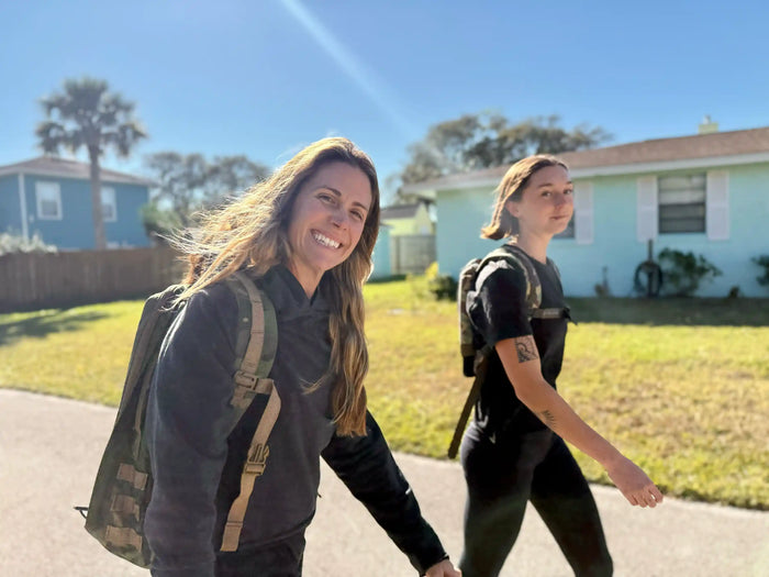 Two women rucking outdoors with GORUCK backpacks on a sunny suburban street