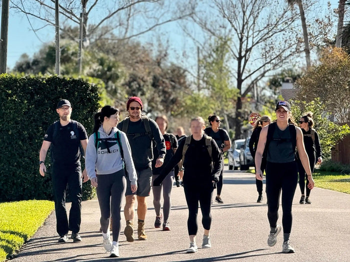 Group of people rucking outdoors wearing GORUCK gear on a sunny neighborhood street
