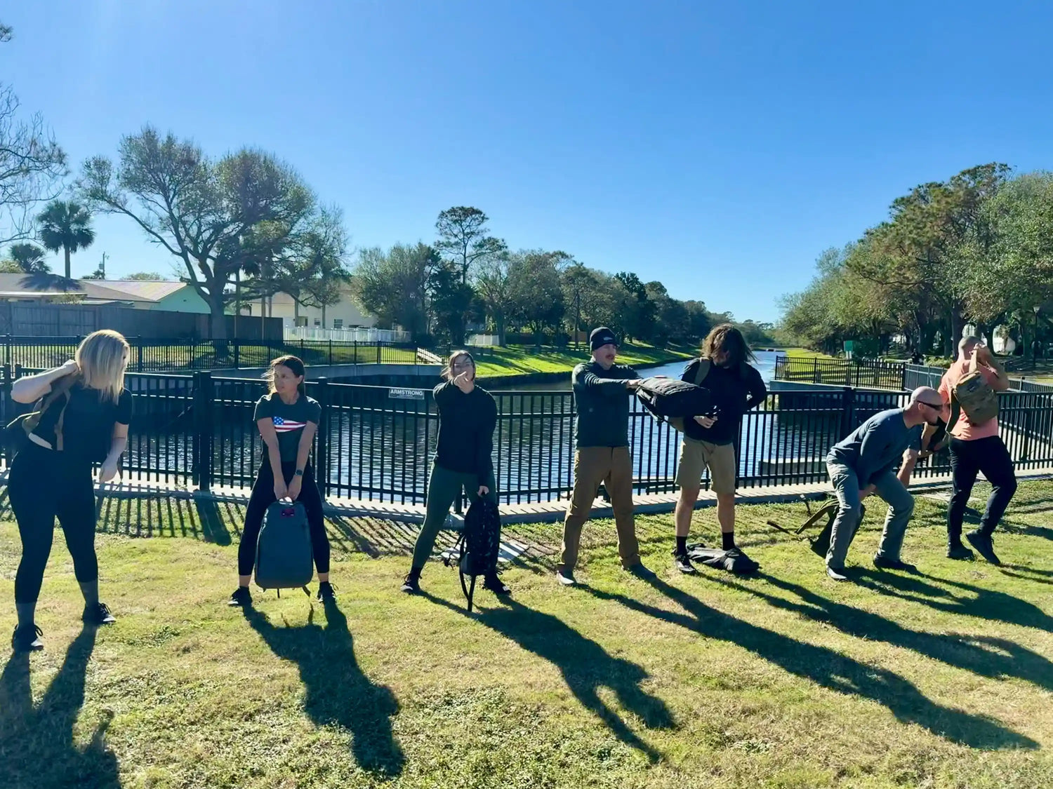 Group rucking workout with GORUCK gear outdoors by a river on a sunny day