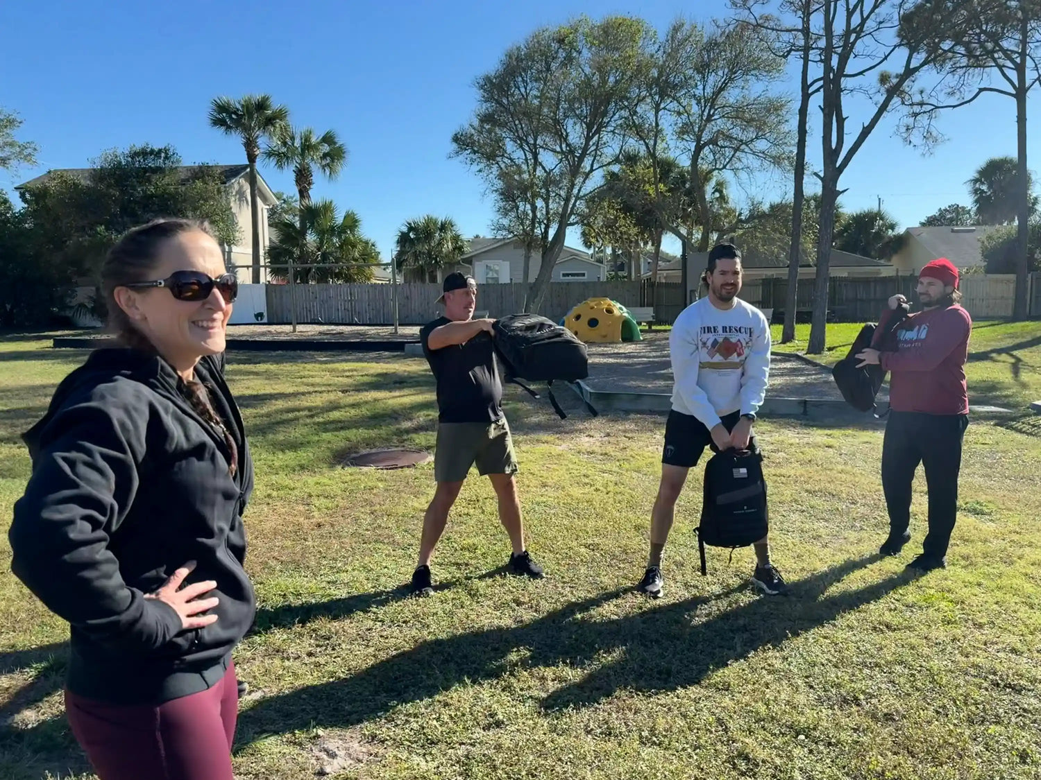 Group outdoor rucking workout with GORUCK gear on sunny day in grassy park