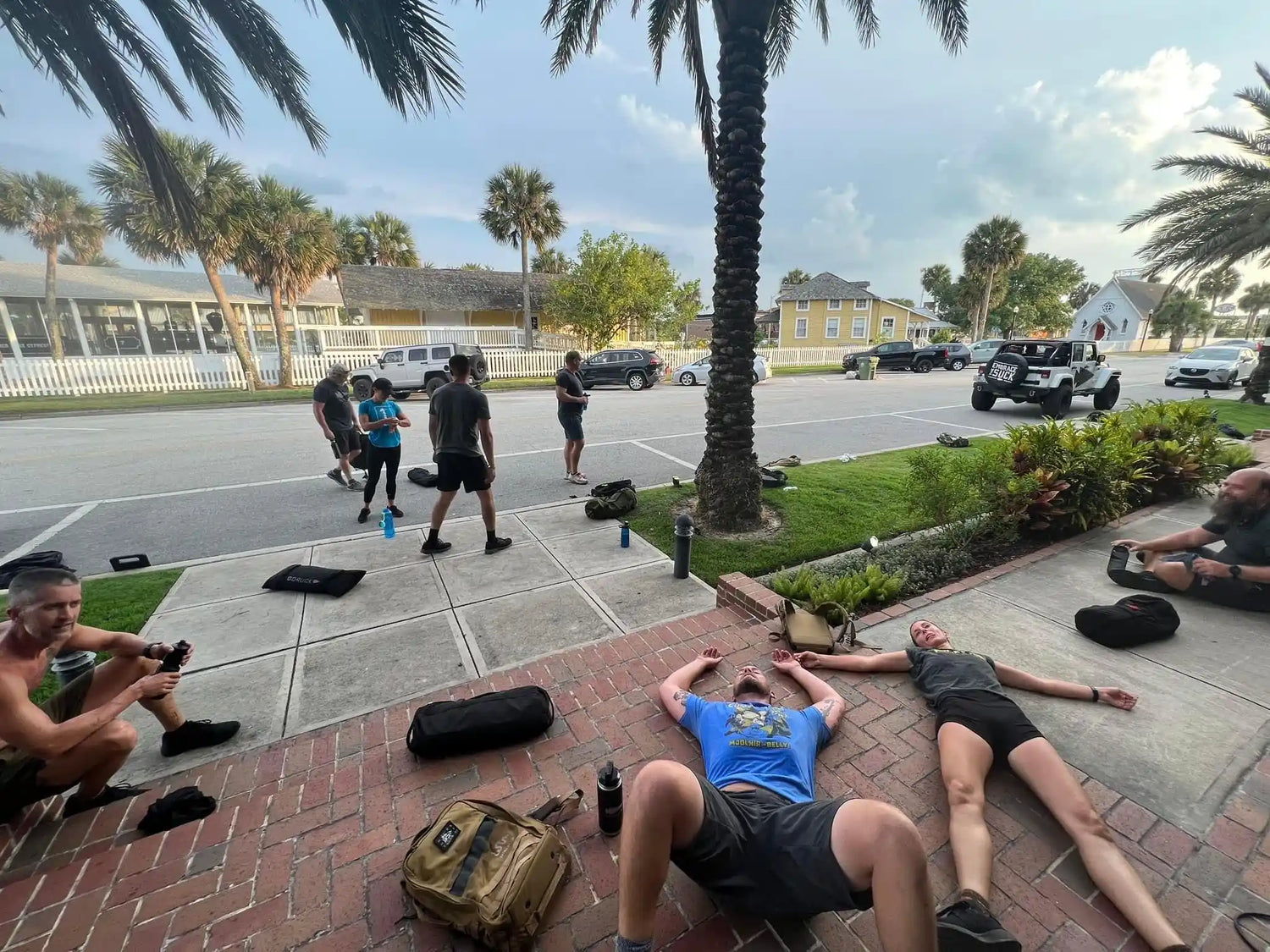 GORUCK group recovering after outdoor rucking workout on brick sidewalk and street