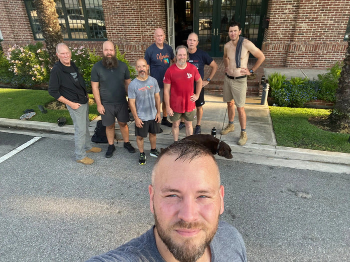 Group of men after a GORUCK rucking event outdoors in front of a brick building