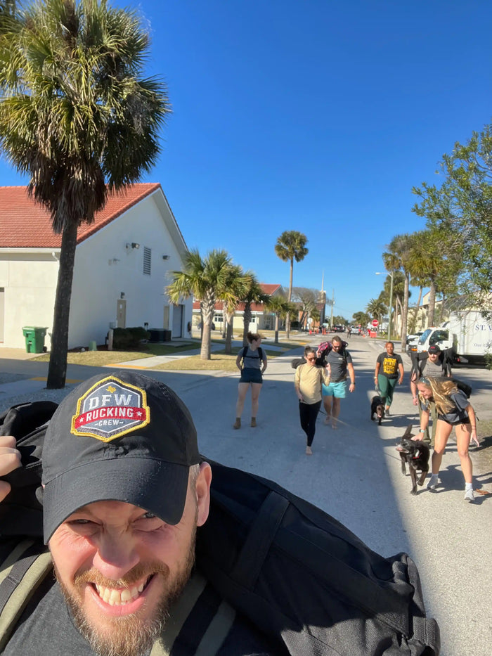 Group rucking event with GORUCK gear under palm trees on a sunny street