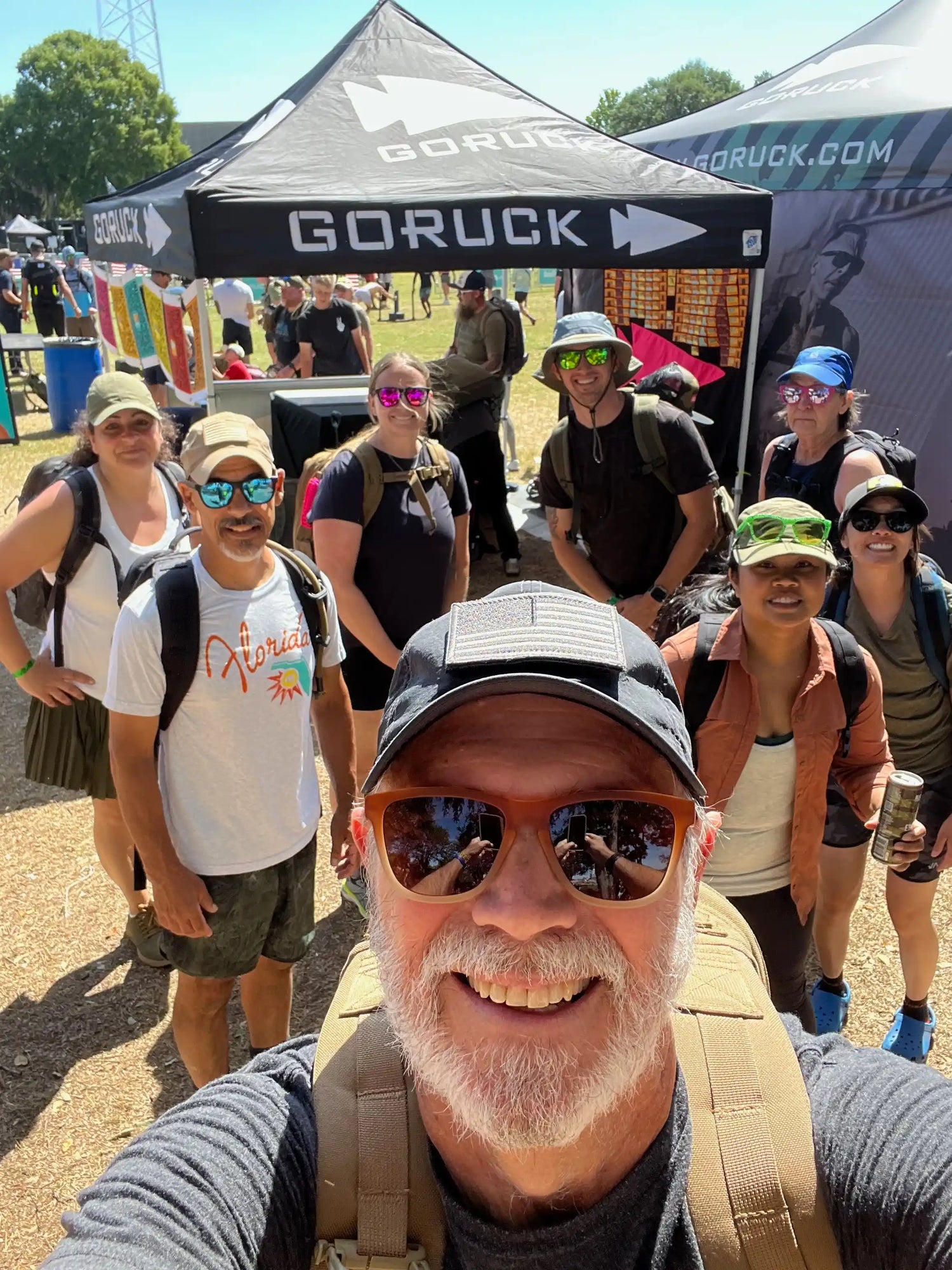 Group of people smiling at GORUCK outdoor event in front of branded tents