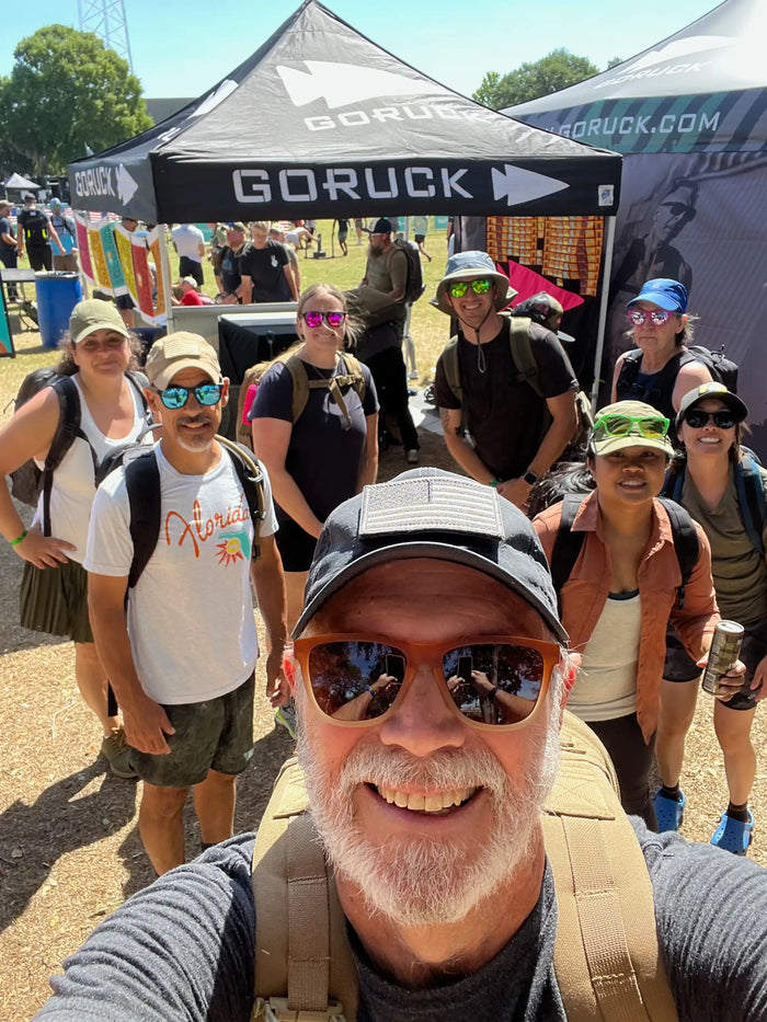 Group of people smiling at GORUCK outdoor event in front of branded tents