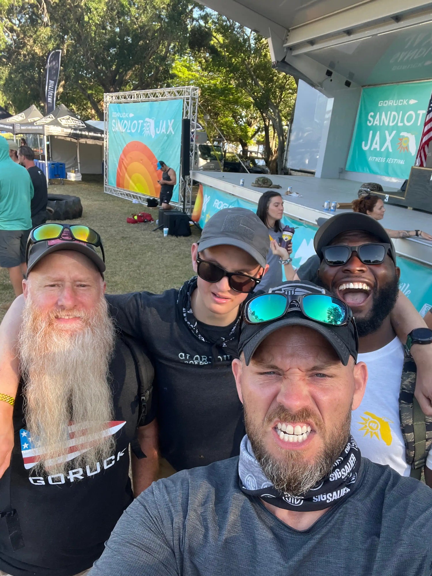 Group of people smiling at GORUCK Sandlot JAX fitness festival outdoor event