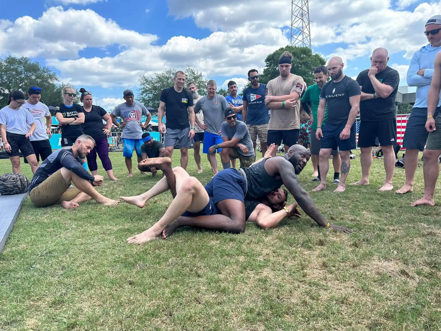 Group training outdoors with goruck.mommunity, participants practicing ground grappling on grass