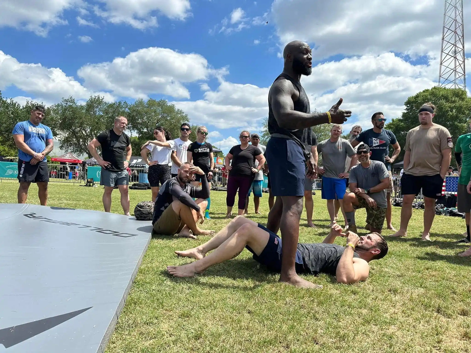 GORUCK outdoor rucking event with instructor demonstrating martial arts on grass with group watching