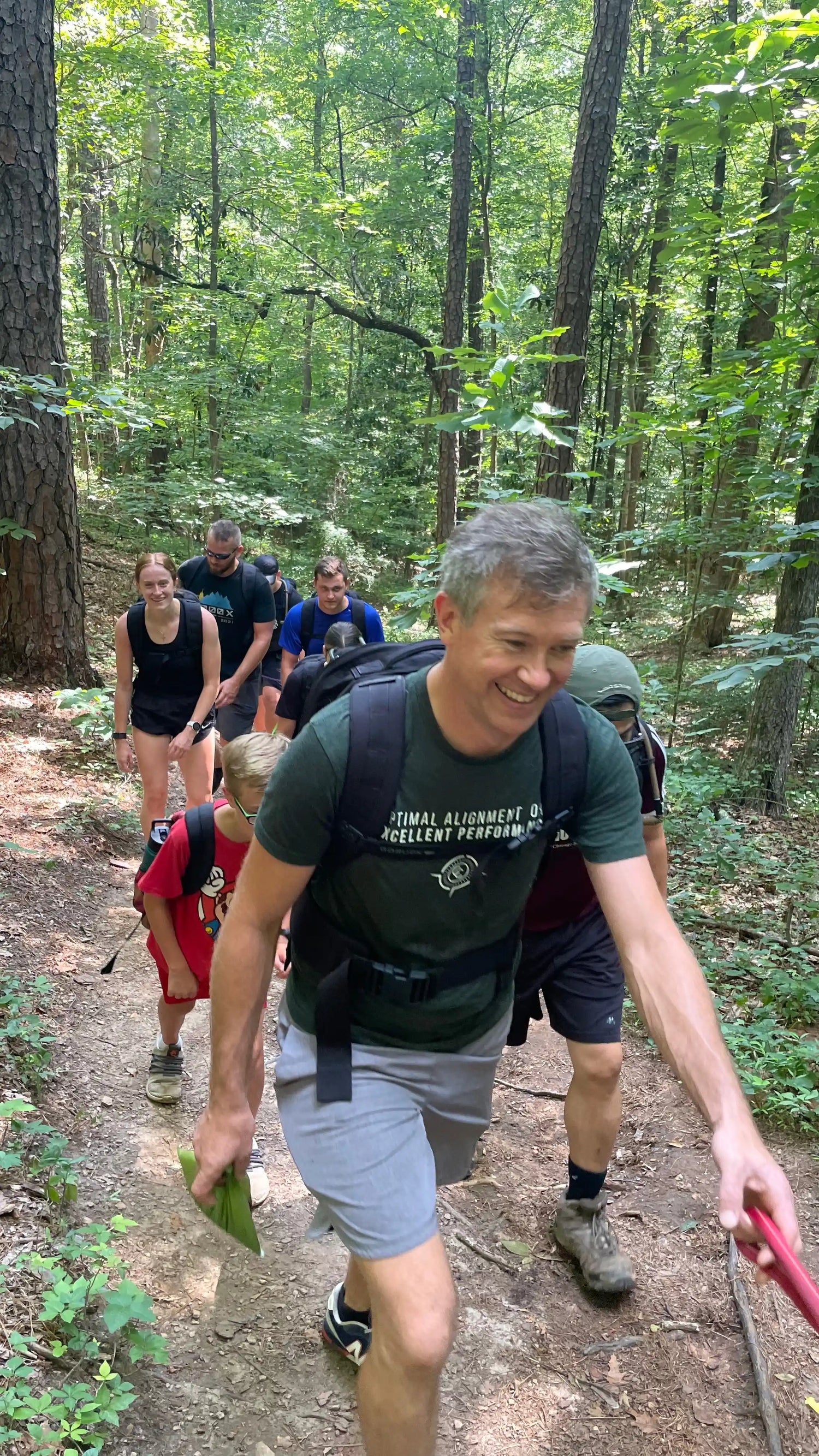 Group rucking on forest trail with GORUCK packs, enjoying outdoor teamwork and fitness.