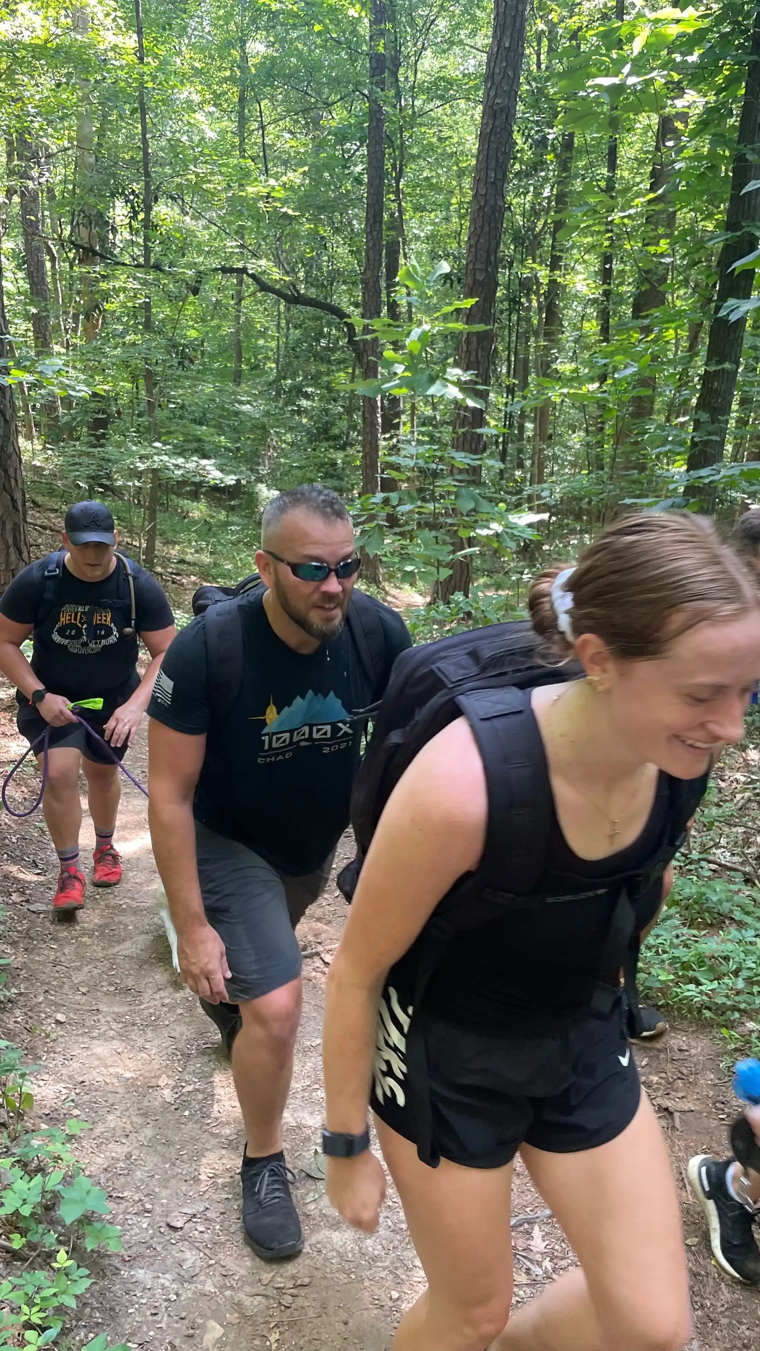 Group rucking with GORUCK gear on a wooded trail, showcasing outdoor fitness and teamwork.