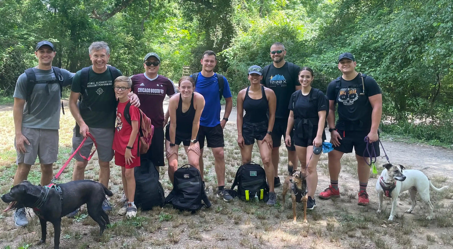 Group of people with rucksacks and dogs outdoors, GORUCK rucking event in nature
