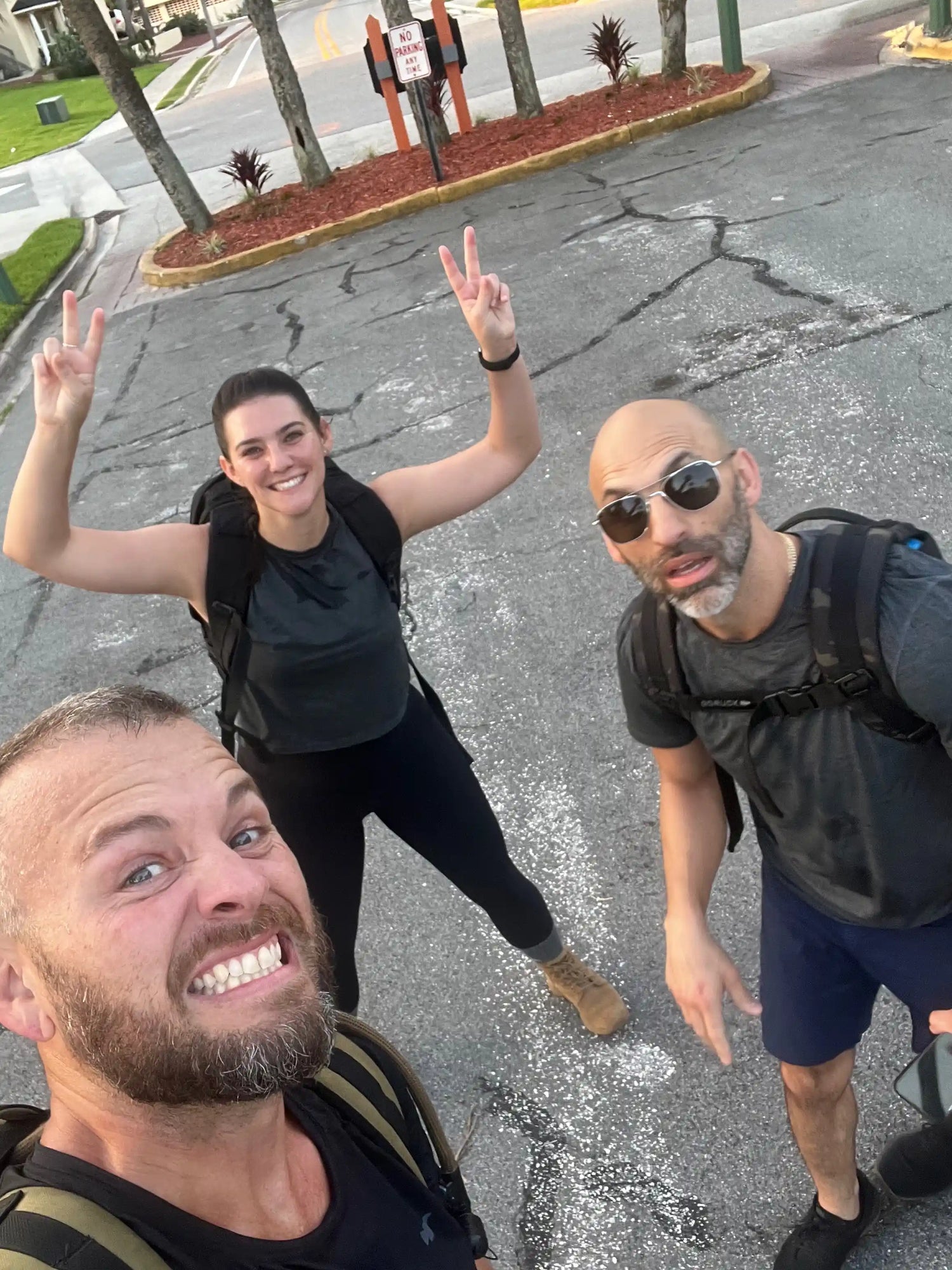 Three people smiling and posing with rucksacks outdoors, showing GORUCK gear in action