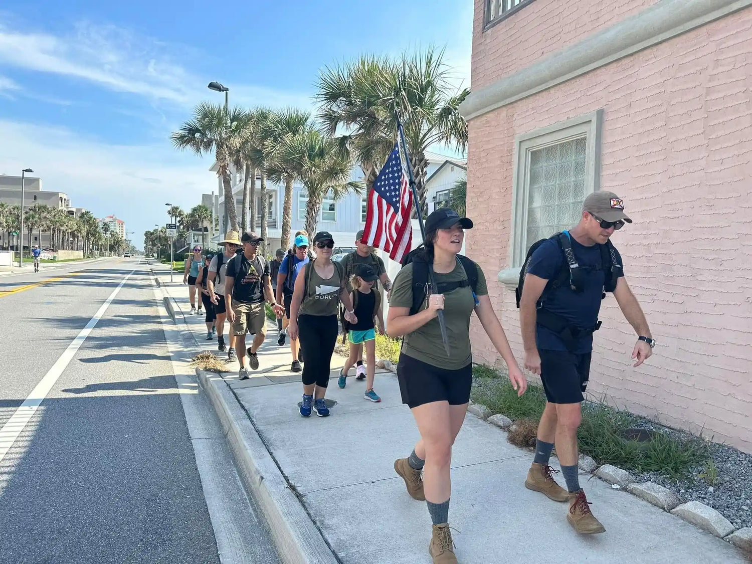 GORUCK team rucking on a city sidewalk, carrying backpacks and an American flag