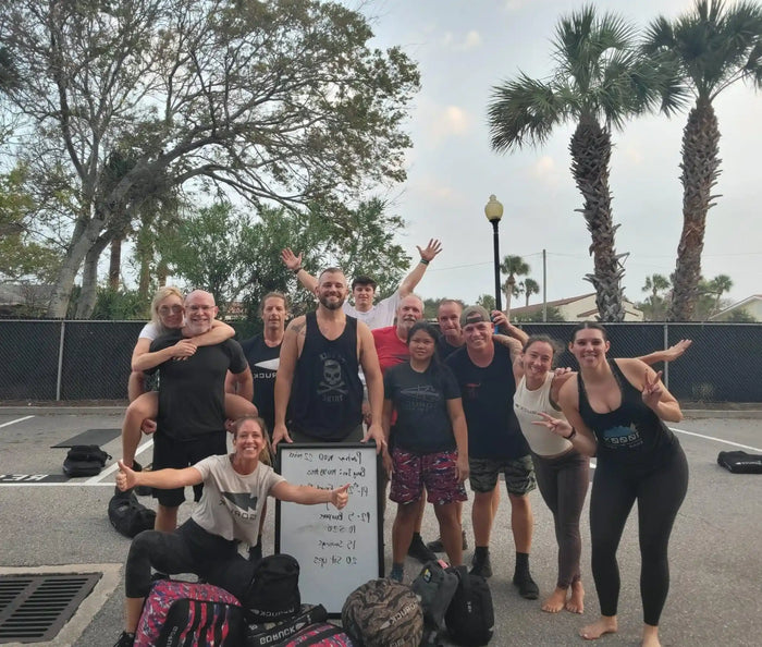 GORUCK group of people posing with rucksacks and whiteboard outdoors in a parking lot