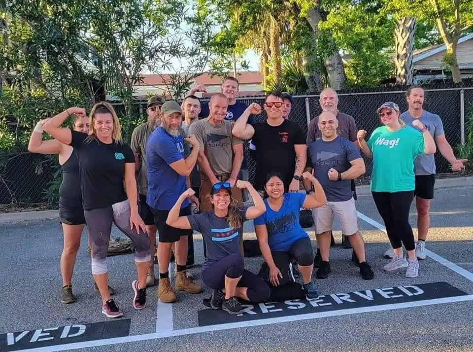 GORUCK group posing outdoors in athletic gear, flexing muscles after a rucking event