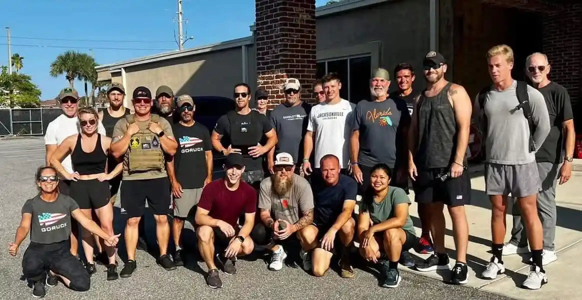 GORUCK group of men and women in athletic gear posing outdoors after rucking event
