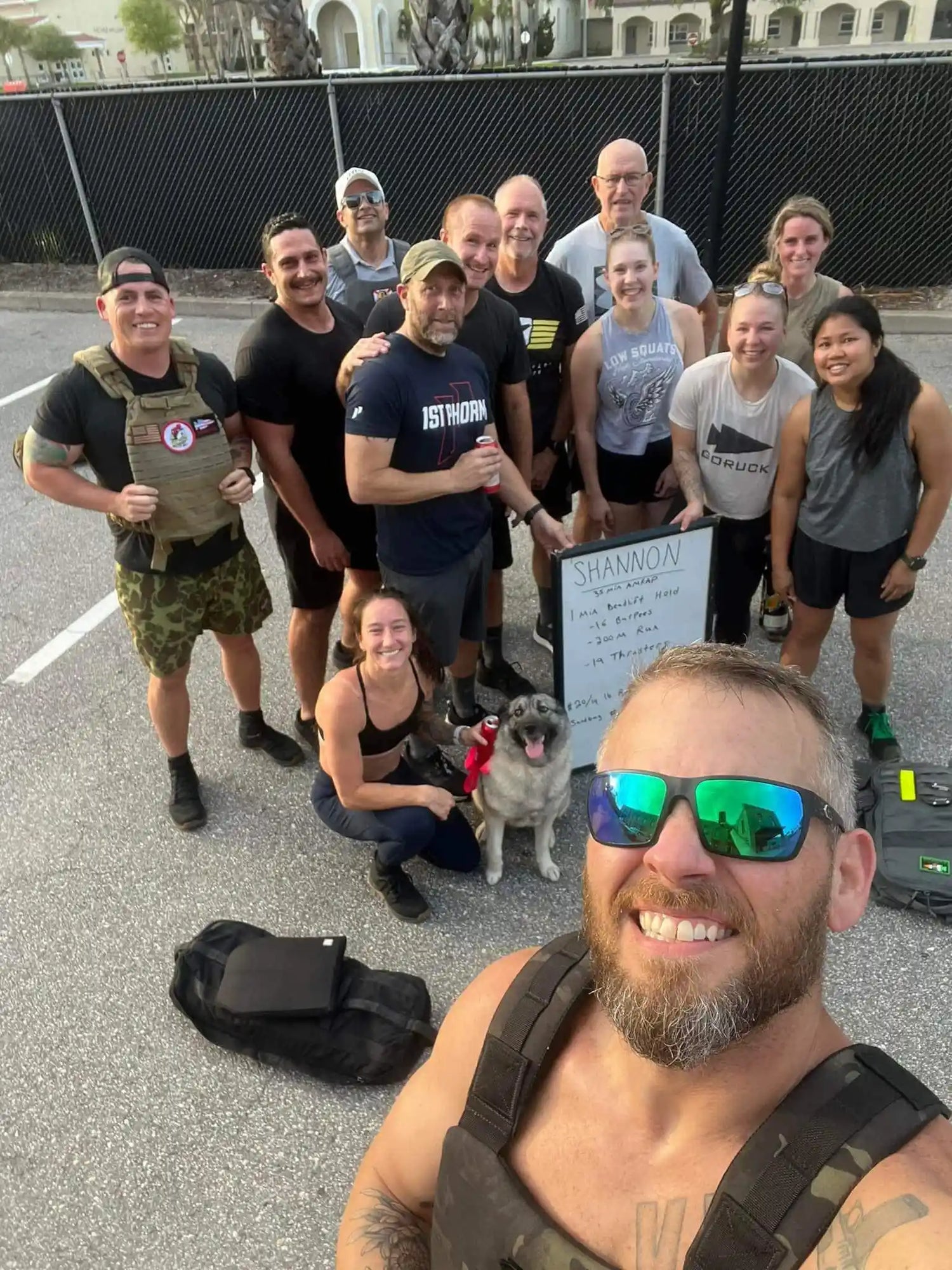 GORUCK group outdoors with rucking gear, dog, and event board, smiling after workout