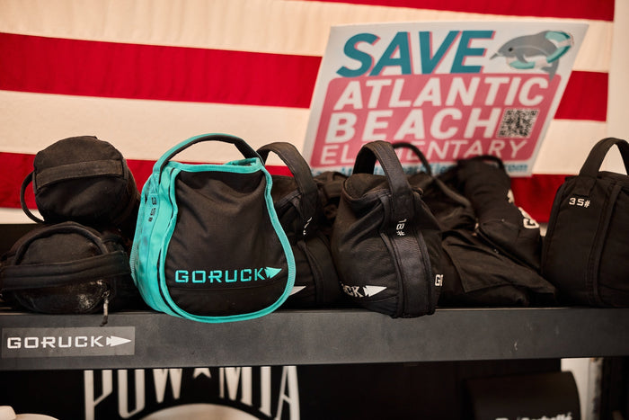 GORUCK rucking gear and sandbags on shelf with American flag and Save Atlantic Beach sign