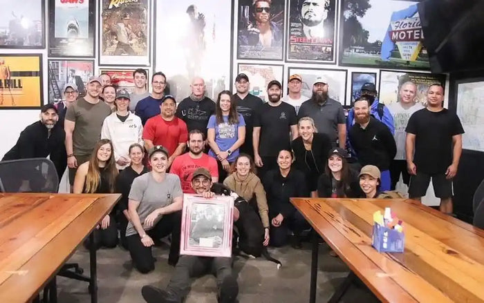 GORUCK team group photo in office with movie posters on wall, rucking community