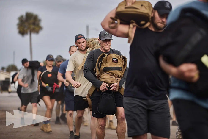 Group of people rucking outdoors with GORUCK backpacks during fitness event training.