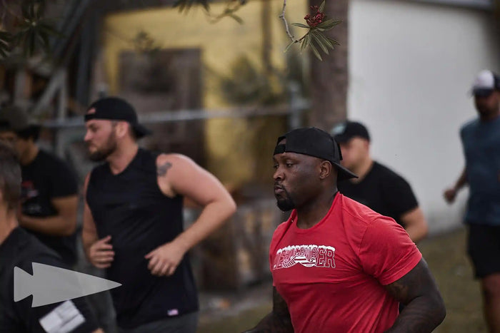 Group of athletic men rucking outdoors, GORUCK gear, focus on teamwork and endurance.