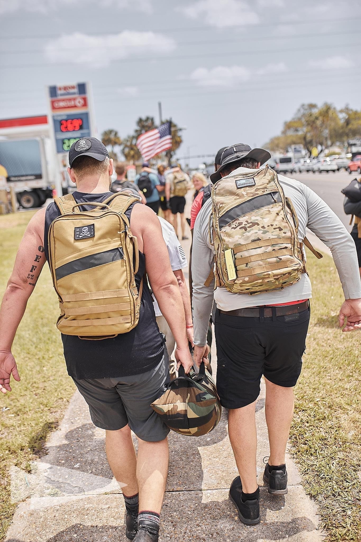 People rucking in GORUCK gear with backpacks on city sidewalk during group event
