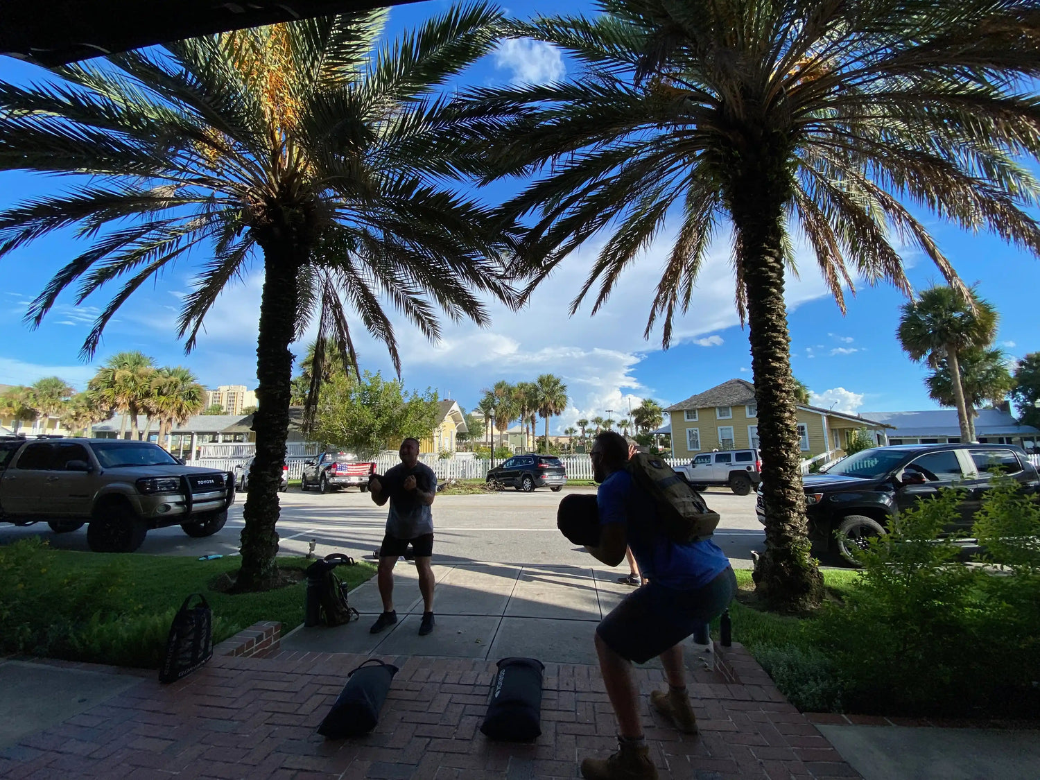 Two people rucking and training outdoors with GORUCK gear under palm trees