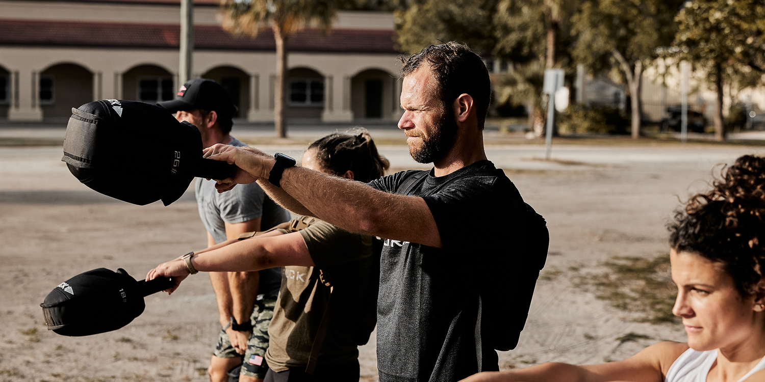 Group outdoor rucking workout with GORUCK sandbags, athletes training in sunlight