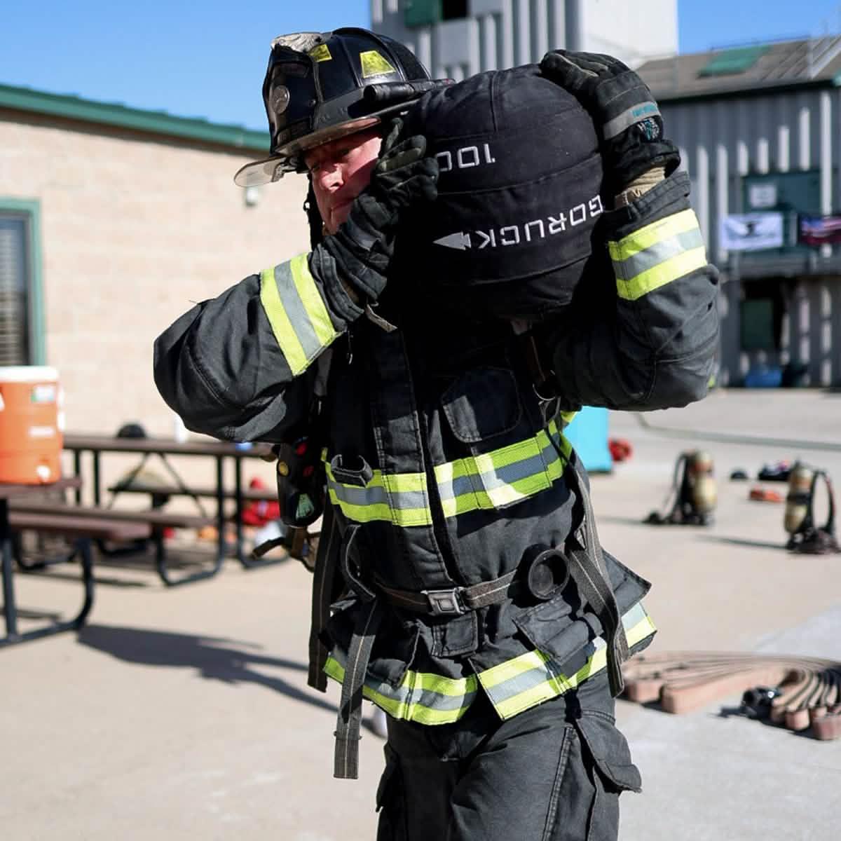 Firefighter training outdoors with GORUCK rucksack, wearing full gear and helmet