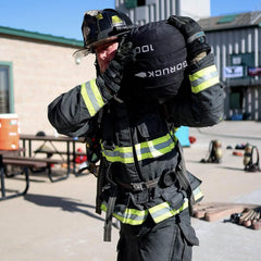 Firefighter training outdoors with GORUCK rucksack, wearing full gear and helmet