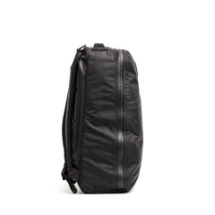 The GR1 USA - Waterproof X-PAC rucksack in black stands upright, shown from the side against a white background, showcasing its rugged, durable gear design.