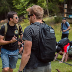 Man wearing black GORUCK rucksack outdoors at rucking event with group participants