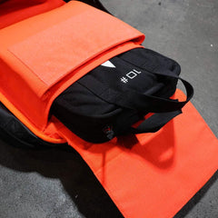 GORUCK 10lb black ruck weight inside bright orange rucksack on concrete floor
