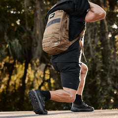 Man outdoors training with GORUCK tan rucksack backpack, black shorts and athletic shoes