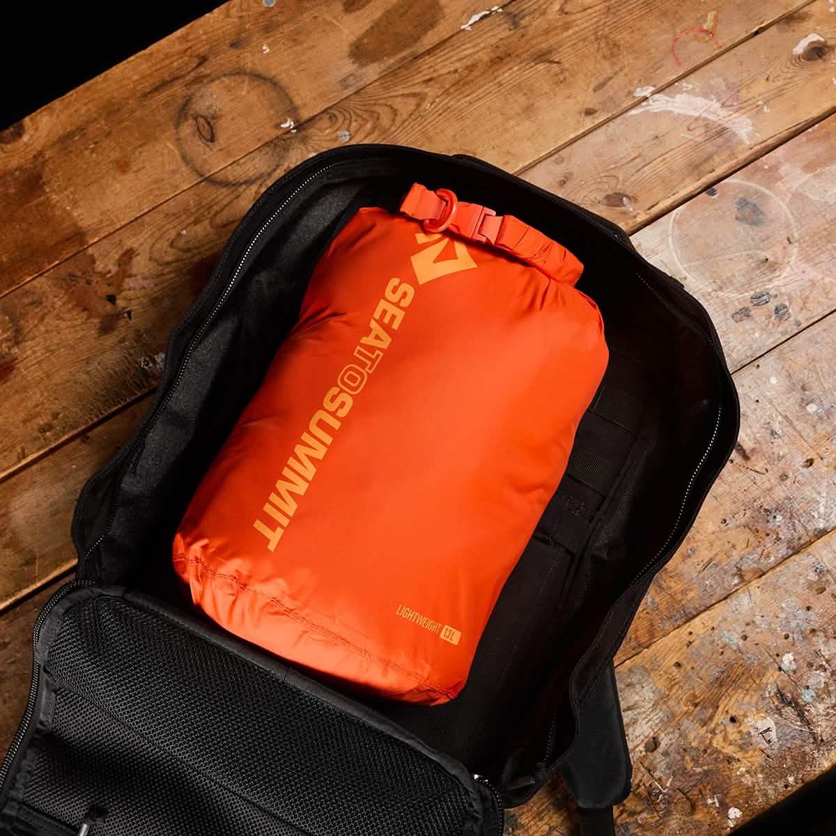 GORUCK rucksack open on wood table with orange Sea to Summit dry bag inside