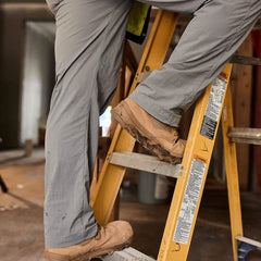 Close-up of person in GORUCK tactical pants and boots climbing a yellow ladder indoors