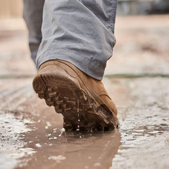 Close-up of GORUCK rucking boot stepping in muddy water, rugged outdoor performance gear