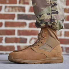 GORUCK brown rucking boot with laces, worn with camouflage pants, brick wall background
