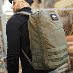 Man wearing GORUCK olive green rucksack outdoors, showcasing durable rucking backpack