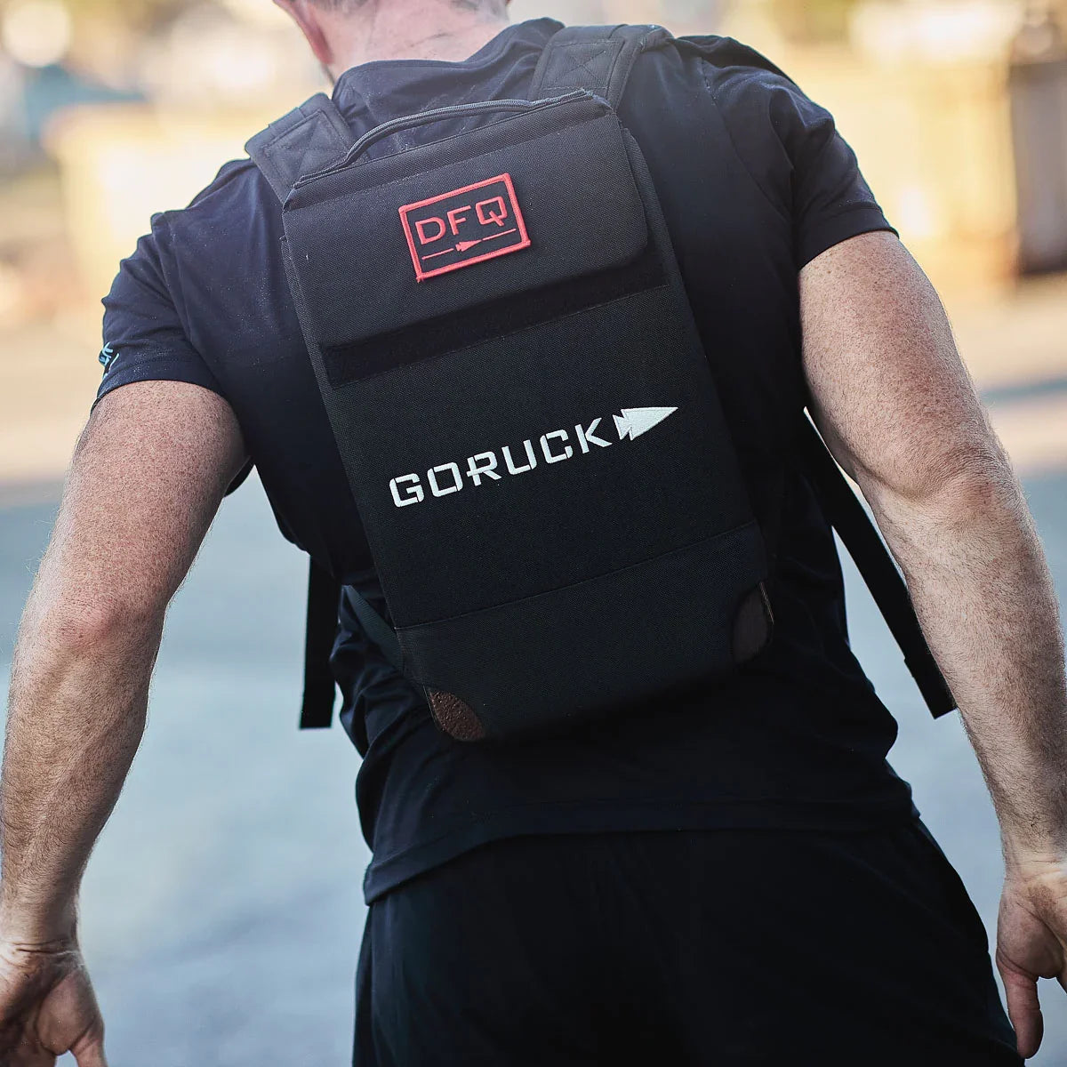 Man wearing GORUCK rucking backpack outdoors, featuring DFQ patch and tough gear design