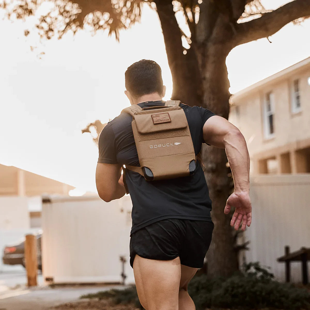 Man running outdoors wearing GORUCK tan rucksack for rucking workout.