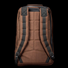 The GR1 rucksack in brown features black padded shoulder straps and a top handle, displayed against a black background.