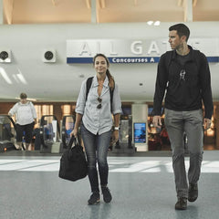 Travelers carrying GORUCK 32L black kit bag in airport terminal, durable rucking gear